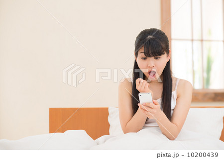 ベッドでスマートフォンを持つ女性 10200439
