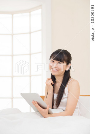 ベッドでタブレットをする女性 ベッドでタブレットをする女性 10200591