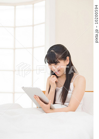 ベッドでタブレットをする女性 ベッドでタブレットをする女性 10200594