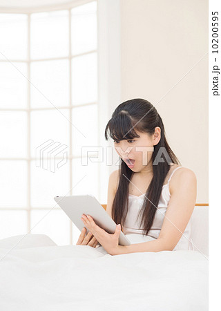 ベッドでタブレットをする女性 ベッドでタブレットをする女性 10200595