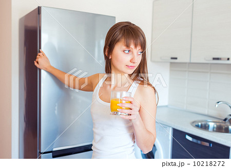 Young caucasian brunette girl with a glass of juice in the kitch Young caucasian brunette girl with a glass of juice in the kitch 10218272
