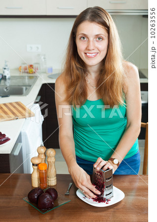 woman grating boiled beets with grater 10263556