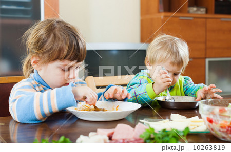 Baby girls eating at wooden table Baby girls eating at wooden table 10263819