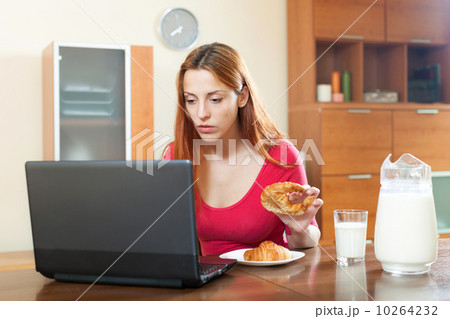 Young famale checking e-mail on laptop during breakfast time Young famale checking e-mail on laptop during breakfast time 10264232