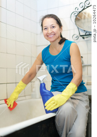 Smiling mature woman cleans bathroom Smiling mature woman cleans bathroom 10264475