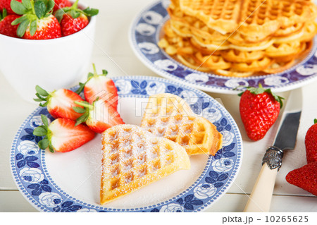 Crisp golden fresh baked waffle topped with strawberries on whit Crisp golden fresh baked waffle topped with strawberries on whit 10265625
