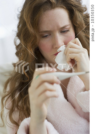 Sick woman looking at thermometer Sick woman looking at thermometer 10350350