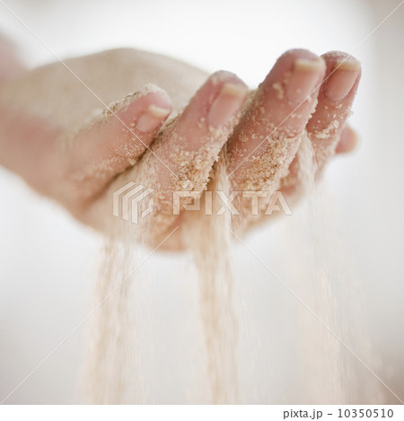 Sand grains falling through hand Sand grains falling through hand 10350510
