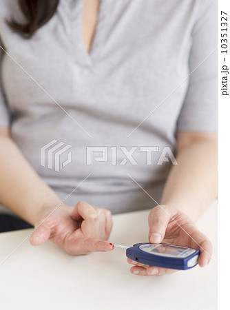 Woman using a blood sugar monitor Woman using a blood sugar monitor 10351327