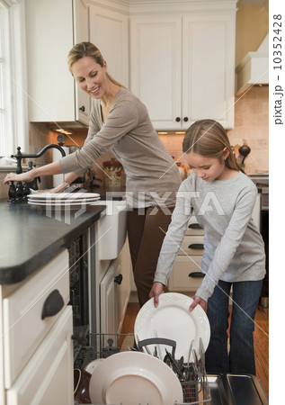 Mother and daughter loading dishwasher 10352428