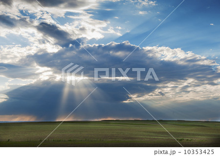 Sunrays shining through clouds over field 10353425