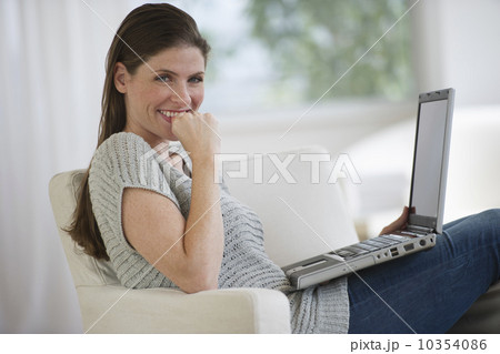 Portrait of smiling woman on armchair with laptop 10354086