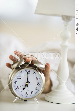 Close-up of man's hand reaching to alarm clock from bed Close-up of man's hand reaching to alarm clock from bed 10354090