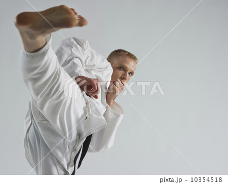 Young man performing karate kick on white background Young man performing karate kick on white background 10354518