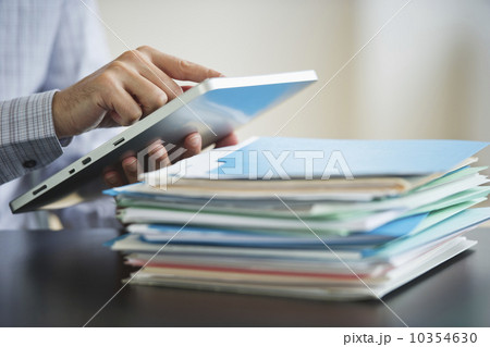 USA, New Jersey, Jersey City, Businessman using digital tablet by paperwork 10354630