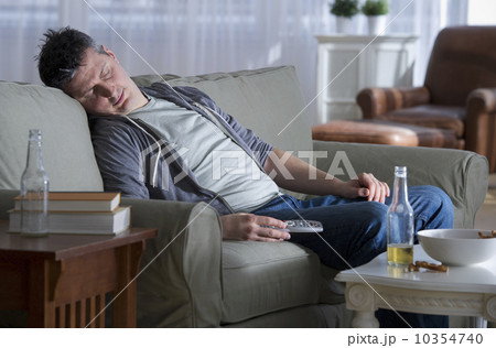 USA, New Jersey, Jersey City, man sitting on sofa, holding remote control and sleeping USA, New Jersey, Jersey City, man sitting on sofa, holding remote control and sleeping 10354740