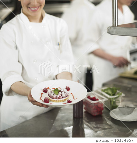 Chefs preparing food in kitchen, women showing dessert 10354957