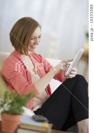 USA, New Jersey, Jersey City, woman sitting on sofa and using digital tablet USA, New Jersey, Jersey City, woman sitting on sofa and using digital tablet 10355089
