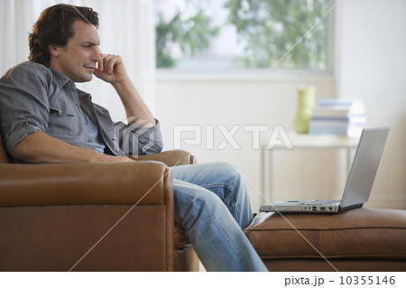 Man leaning on armchair with laptop Man leaning on armchair with laptop 10355146