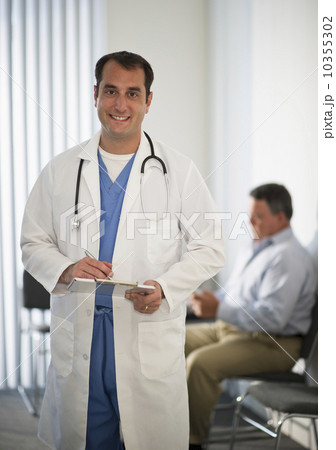 USA, New Jersey, Jersey City, Portrait of doctor holding medical results with male patient in background USA, New Jersey, Jersey City, Portrait of doctor holding medical results with male patient in background 10355302