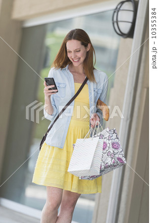 Woman with shopping bags using phone Woman with shopping bags using phone 10355384