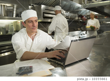 Chefs preparing food, one working on laptop 10355661