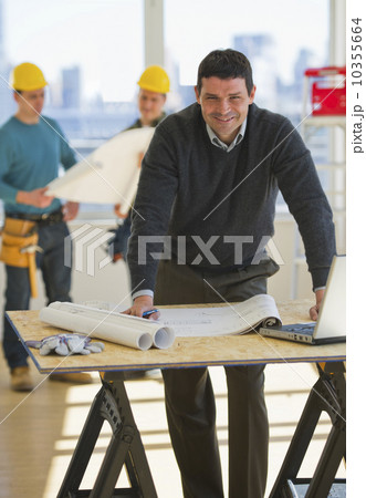 USA, New Jersey, Jersey City, architect preparing blueprint, construction workers in background 10355664