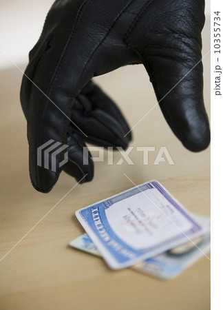 Close up of thief's hand in black glove stealing driver's license, studio shot 10355734
