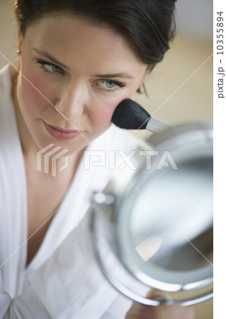 USA, New Jersey, Jersey City, woman applying blush on cheekbones USA, New Jersey, Jersey City, woman applying blush on cheekbones 10355894