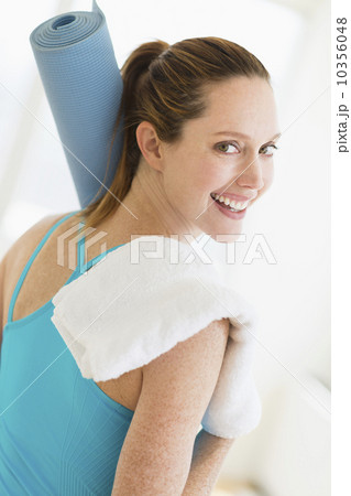 Woman carrying exercise mat and towel 10356048