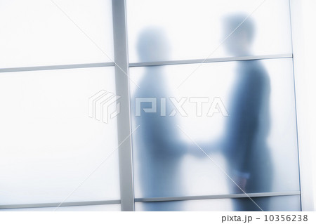 Silhouettes of two businessmen behind glass door Silhouettes of two businessmen behind glass door 10356238