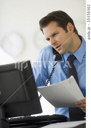 Businessman working on computer and talking on the phone Businessman working on computer and talking on the phone 10356362