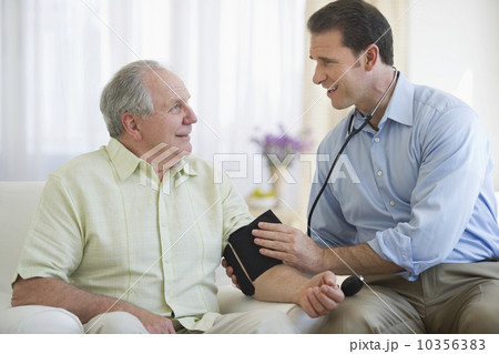 Smiling man taking senior man's blood pressure 10356383