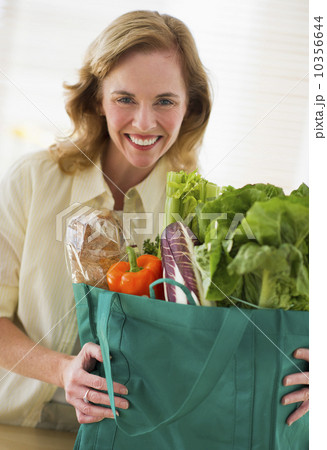 USA, New Jersey, Jersey City, Portrait of woman holding grocery bag in kitchen 10356644