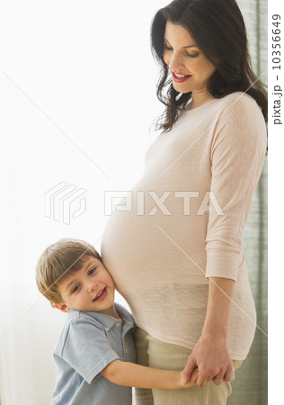 Boy (4-5) putting ear to pregnant mother's belly Boy (4-5) putting ear to pregnant mother's belly 10356649