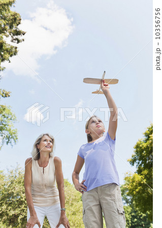 Girl (10-11) and grandmother playing with toy plane 10356756