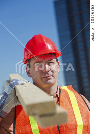 USA, New Jersey, Jersey City, construction worker carrying planks 10356868