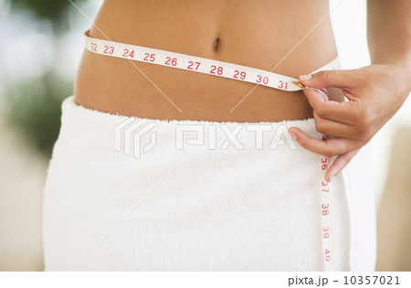 Midsection of woman measuring waist Midsection of woman measuring waist 10357021