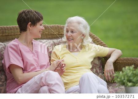 Senior woman and nursing assistant relaxing on outdoor sofa 10357271