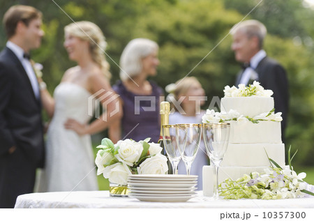 Wedding table with champagne and cake, people in background 10357300