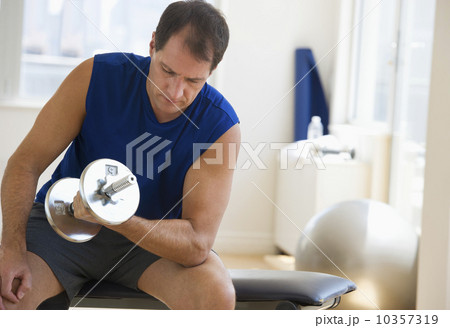 Mature man lifting weights in gym 10357319