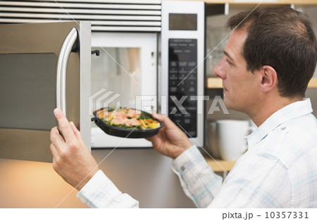 Man inserting meal in microwave oven 10357331