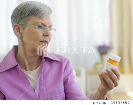 Senior woman looking at pill bottle Senior woman looking at pill bottle 10357366