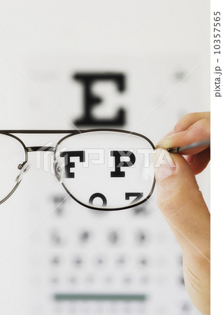 Close up of hand holding glasses above eye chart, studio shot Close up of hand holding glasses above eye chart, studio shot 10357565