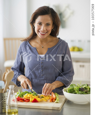 USA, New Jersey, Jersey City, smiling woman preparing food in kitchen 10357569