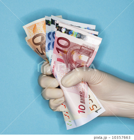Hand in surgical glove holding banknotes 10357663