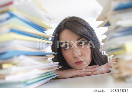 Young woman looking at stack of documents at desk 10357852
