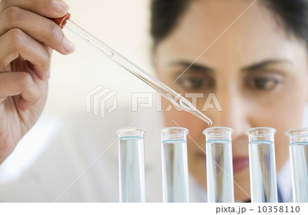 Scientist pipetting liquid into test tubes 10358110