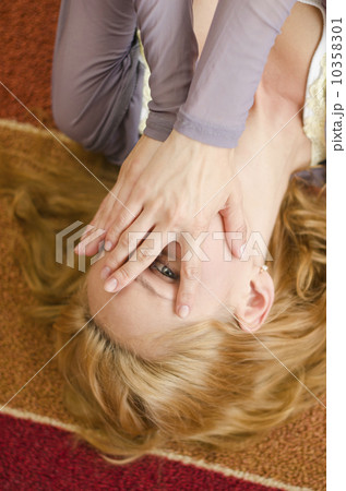 Woman lying on floor covering eyes 10358301