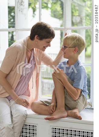Mother and son (10-11) sitting on window seat 10358487